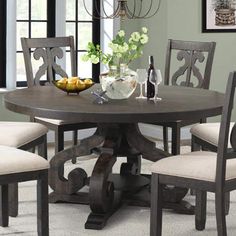 a dining room table with four chairs and a bowl of fruit on the table next to it