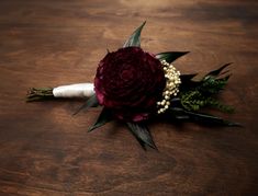 a bridal boutonniere with flowers and pearls on it sitting on a wooden table