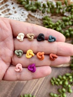 a hand holding seven different colored beads in it's palm, next to green beans