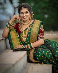 a woman in a green and gold sari sitting on steps with her hands behind her head