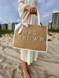 a woman holding a bag with the words mrs brown on it and a white bow