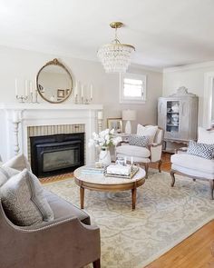 a living room filled with furniture and a fire place under a chandelier in front of a fireplace