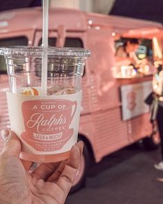 a cup of kaffir's coffee is being held up in front of a pink truck