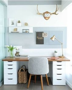 a white desk topped with a chair next to a wall mounted deer's head