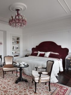 a bedroom with a bed, two chairs and a chandelier