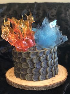 a cake with frosting and colorful decorations on it's top, sitting on a wooden stand