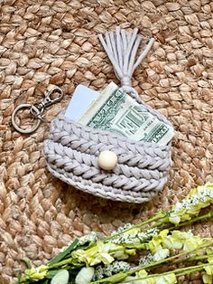 a purse with money and flowers sitting on a woven table cloth next to it's keychain