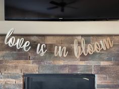 a fireplace with a sign that says love is an bloom on the wall above it