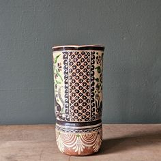 a brown and white vase sitting on top of a wooden table next to a wall