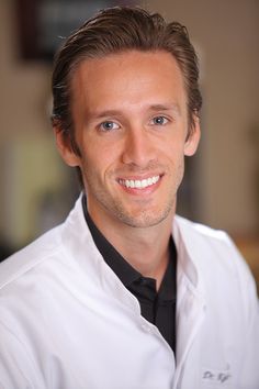 a man wearing a white shirt and black tie smiling at the camera with his eyes wide open