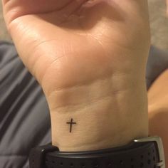 a person with a small cross tattoo on their wrist