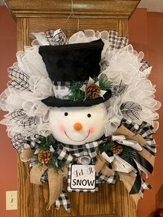 a snowman wreath with a top hat and bow tie hanging from the front door