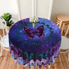 a round table covered with purple butterflies and flowers on top of wooden floor next to white chairs