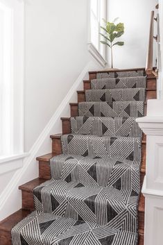 the stairs are decorated with black and white geometric rugs, along with a potted plant