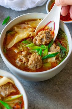 two bowls of soup with meatballs and vegetables being spooned into the bowl by someone's hand