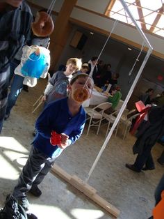 a group of people standing in a room with donuts hanging from the ceiling above them