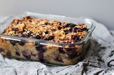 a glass dish filled with blueberry crumbles on top of a gray blanket