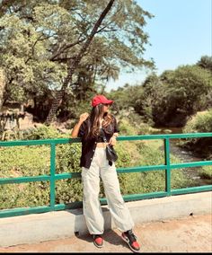 a woman standing on a bridge with her hands in her pockets