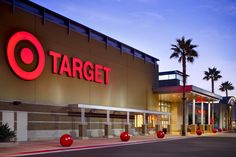 a target store at dusk with palm trees in the foreground and red balls on the sidewalk