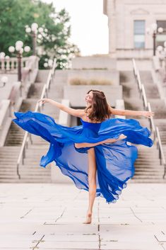 a woman in a blue dress is dancing on steps