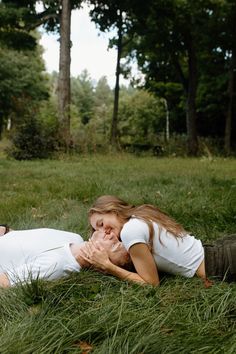 two people laying in the grass with their hands on each other's chests