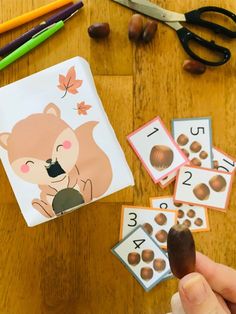 a person is playing with some sort of animal card game on the table next to scissors and pencils