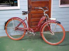 a red bicycle parked in front of a blue house