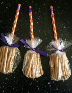 three cookies wrapped in plastic and tied with purple ribbon are sitting on a counter top