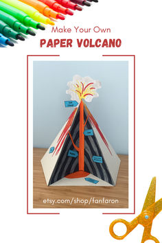 an origami paper volcano with scissors and colored crayons in the background