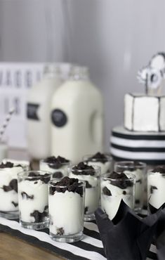 desserts are arranged on a table with black and white decor