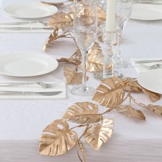 the table is set with silverware and gold leaf napkins for an elegant dinner