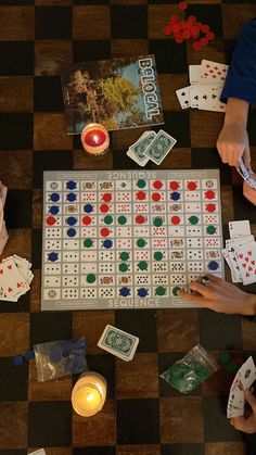 top-down overhead photo of sequence (the board game) splayed across a black and brown wooden coffee table as three people are playing the game, two candles are lit on the table Checkers Game Aesthetic, Family Board Game Night Aesthetic, 30th Birthday Cabin Weekend, Family Board Games Aesthetic, Cozy Cabin Vibes, Cabin Party Aesthetic, Board Game Coffee Table, Family Game Night Aesthetic, Summer Cabin Aesthetic