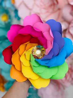 a colorful flower being held by someone's hand