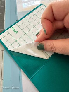 someone is cutting out a piece of paper on top of a crafting mat with scissors