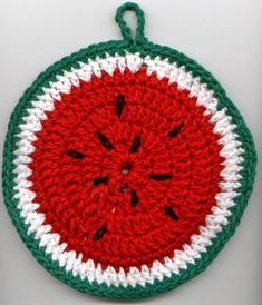 a crocheted watermelon ornament hanging on a white wall with green trim