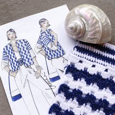 two crocheted pieces of clothing next to a seashell on top of a piece of paper