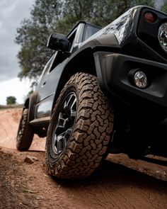 the front end of a black jeep parked on dirt