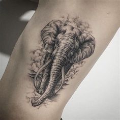 an elephant tattoo on the leg of a woman's leg, with clouds in the background