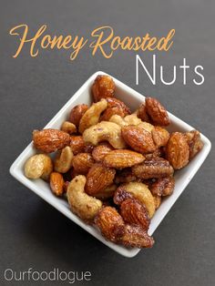 a square white bowl filled with nuts on top of a black table next to the words honey roasted nuts