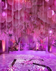 a room filled with lots of pink balloons and hanging flowers on the ceiling above it