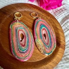 pair of colorful earrings on wooden plate with pink flower