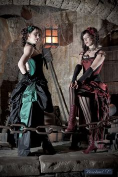 two beautiful women dressed in gothic clothing posing for the camera with chains around their ankles