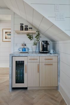 a kitchen area with wooden cabinets and shelves under a stair case that leads up to the second floor