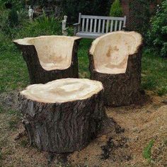 two wooden chairs sitting next to each other on top of a grass covered field near a bench