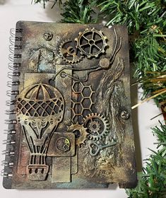 an altered book is sitting on top of a christmas tree with gears and chains attached to it