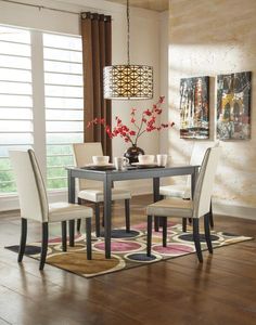 a dining room table with chairs and a rug on the floor in front of it