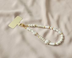 a white beaded necklace with a gold plated cross on it, laying on a bed