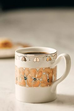 a coffee cup sitting on top of a counter next to a piece of bread in the background