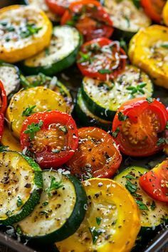 a pan filled with lots of different types of tomatoes and zucchini on top of it