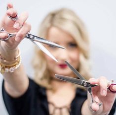 a woman holding two pairs of scissors in her hands